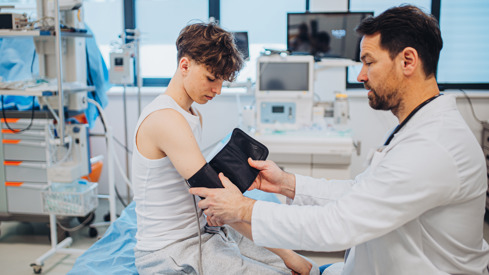 Illustrasjonsfoto av fastlege i hvit frakk og en tenåringsgutt som er pasient