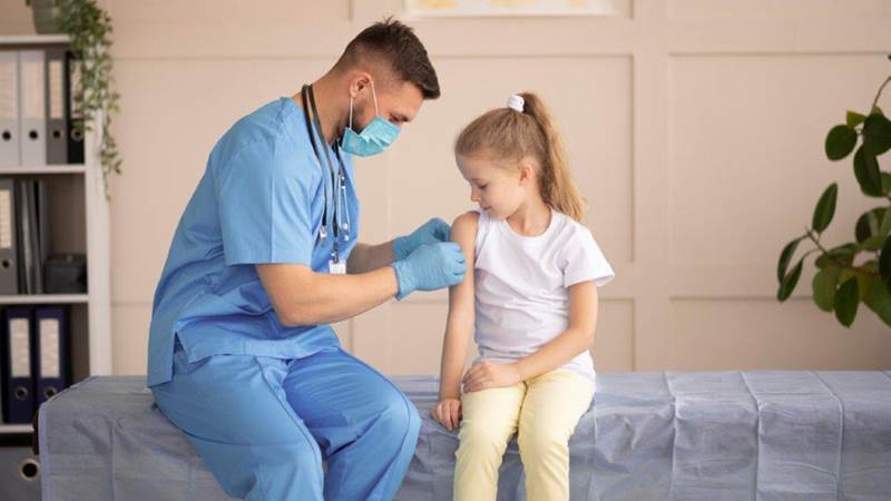 En lege setter et plaster på overarmen til en jente