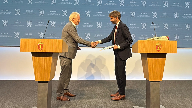 Jan Oddvar Skisland, som ledet utvalget som vurderte prioritering av folkehelsetiltak, tar helse- og omsorgsminister Jan Christian Vestre i hand. Vestre holder utvalgets utredning i den andre handa.