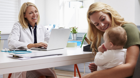 Illustrasjonsfoto av kvinnelig fastlege i møte med mor og hennes nyfødte barn på legekontor