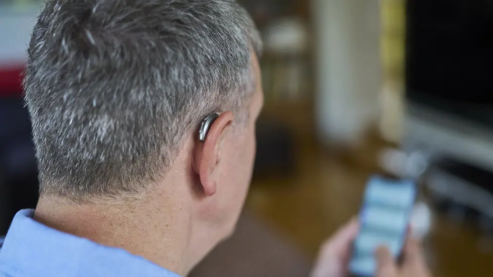 Bakhodet til en eldre mann med høreapparat på øret