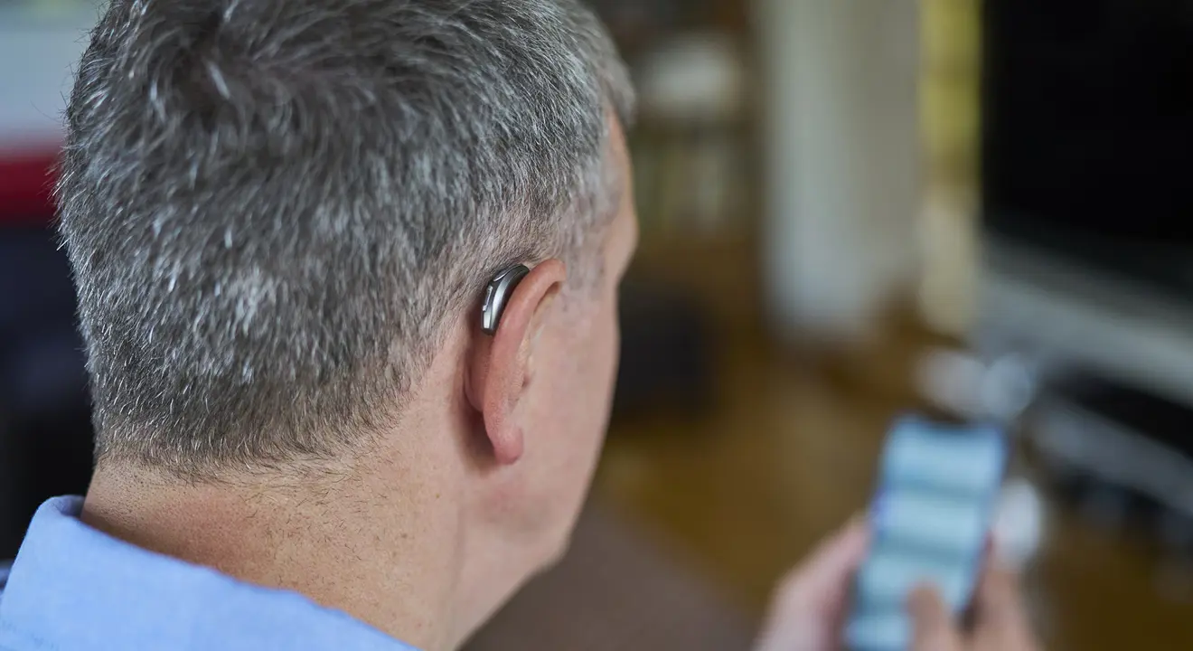 Bakhodet til en eldre mann med høreapparat på øret