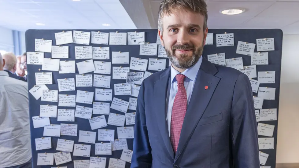 Helse- og omsorgsminister Jan Christian Vestre står foran en vegg med masse lapper, skrevet av gjester på Livslosen