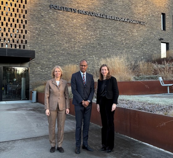 To kvinner og en mann i midten av kvinnene foran et stort bygg.