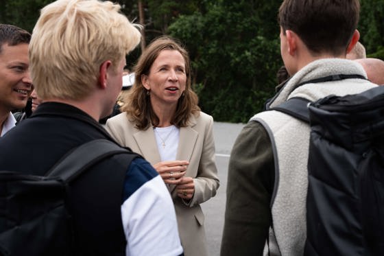 Kvinne står mellom to unge menn som står med ryggen til henne.