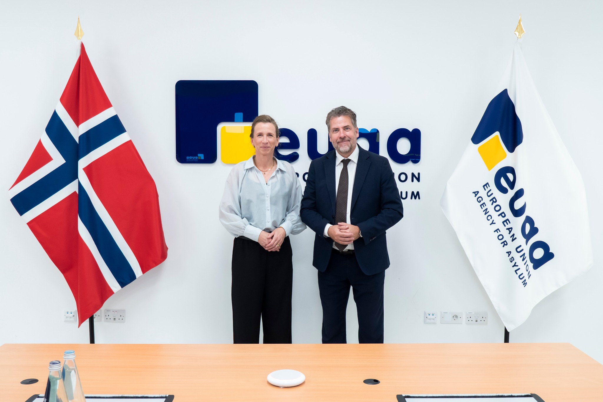 Statsråden sammen med assisterende direktør i EUAA og det norske flagget.