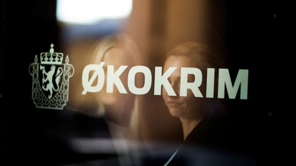Refleksjon av to kvinner med lyst hår i et vinduet. På vinduet står det «Økokrim» med store hvite bokstaver.