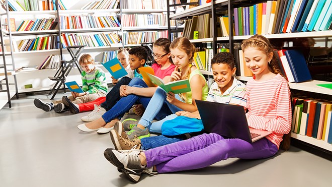 Bilde av barn som leser bok i et bibliotek