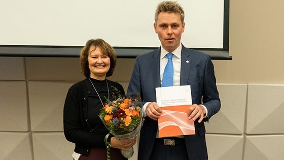 Bilde av  Ingvild Marheim Larsen, leder av akkrediteringsutvalget med blomster og forsknings- og høyere utdanningsminister Ola Borten Moe som holder rapporten.