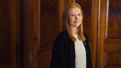 Kvinne står og smiler til kamera