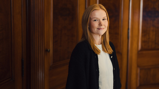 Kvinne står og smiler til kamera