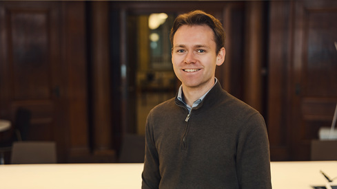 Mann står og smiler mot kamera