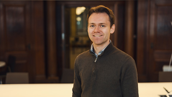 Mann står og smiler mot kamera