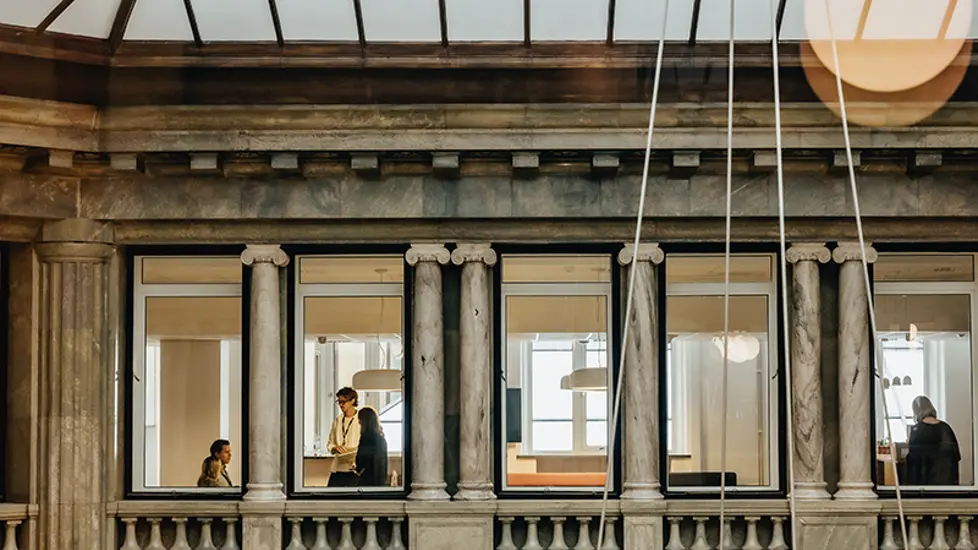 Bilde av kontorlokaler med ansatte igjennom vinduer.