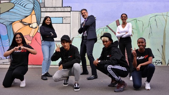 Kultur- og likestillingsminister Abid Q. Raja med ungdommer fra Ammerudklubben og Kulturhjerte foran en vegg med grafitti på Ammerud.