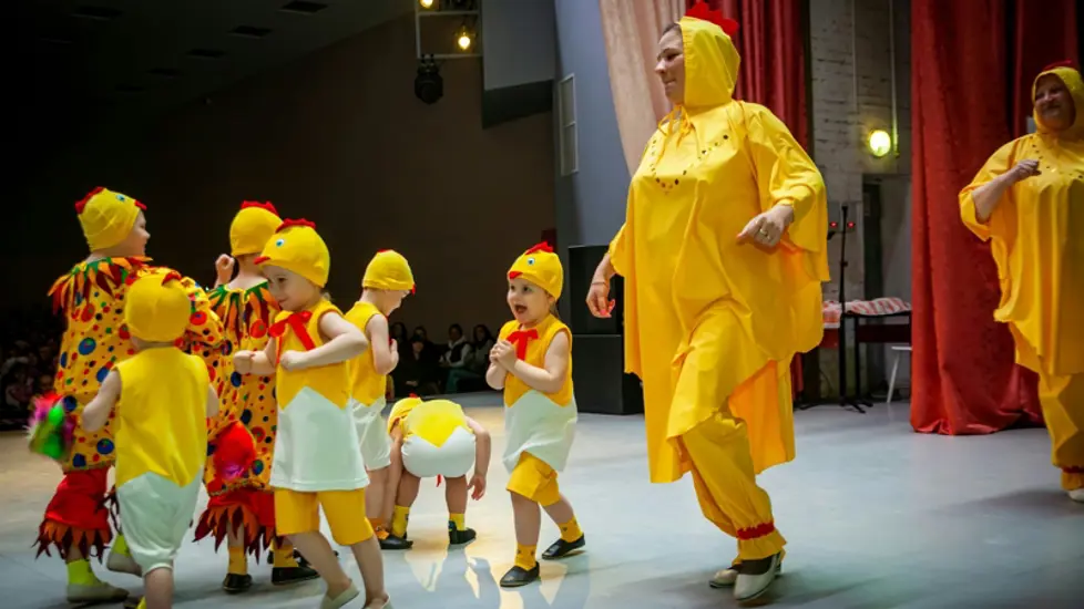 Illustrasjonsbilde av barn og et par voksne utkledd som kyllinger på en teaterscene