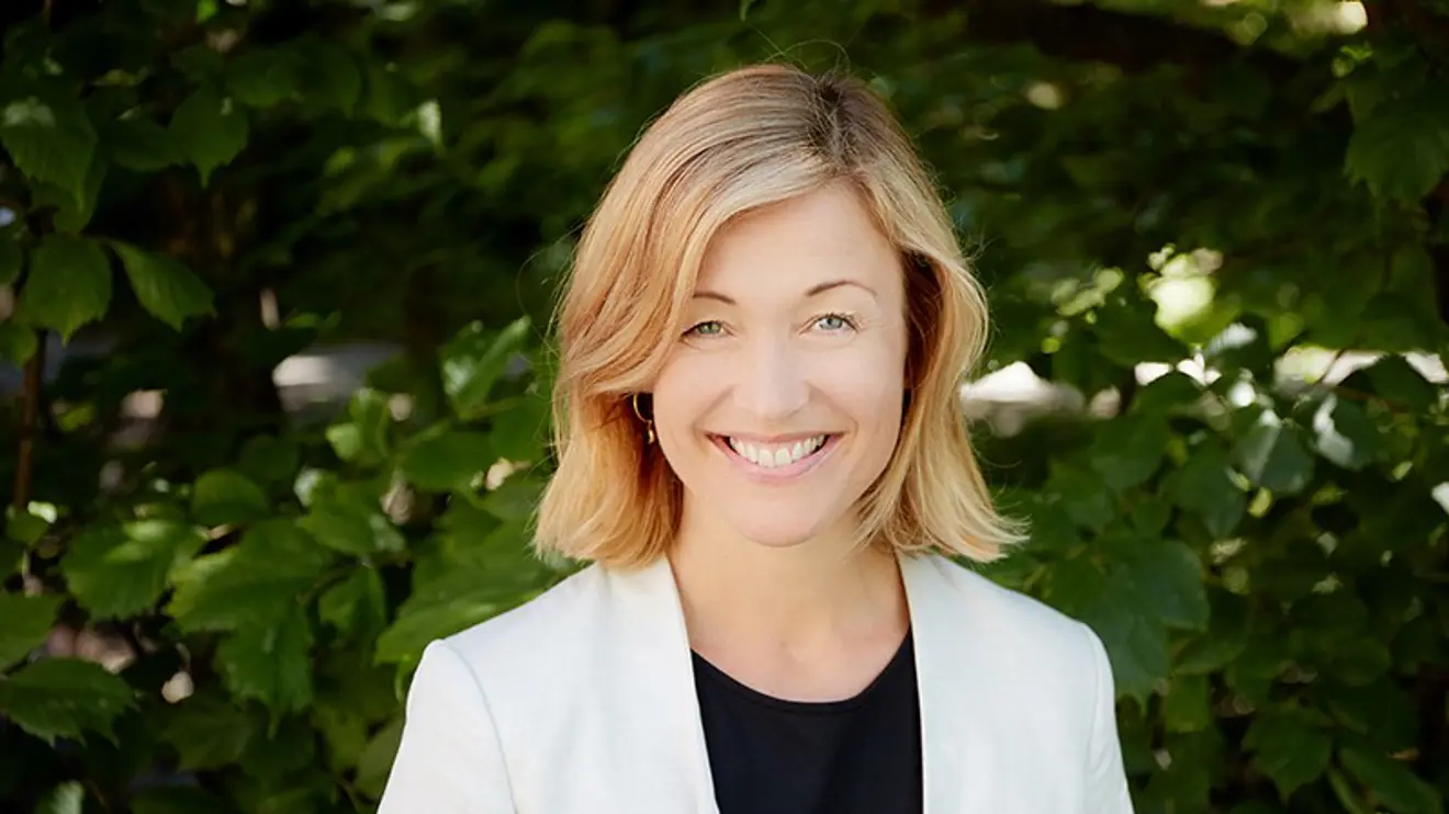 Portrettbilde med grønt løvverk i bakgrunnen.