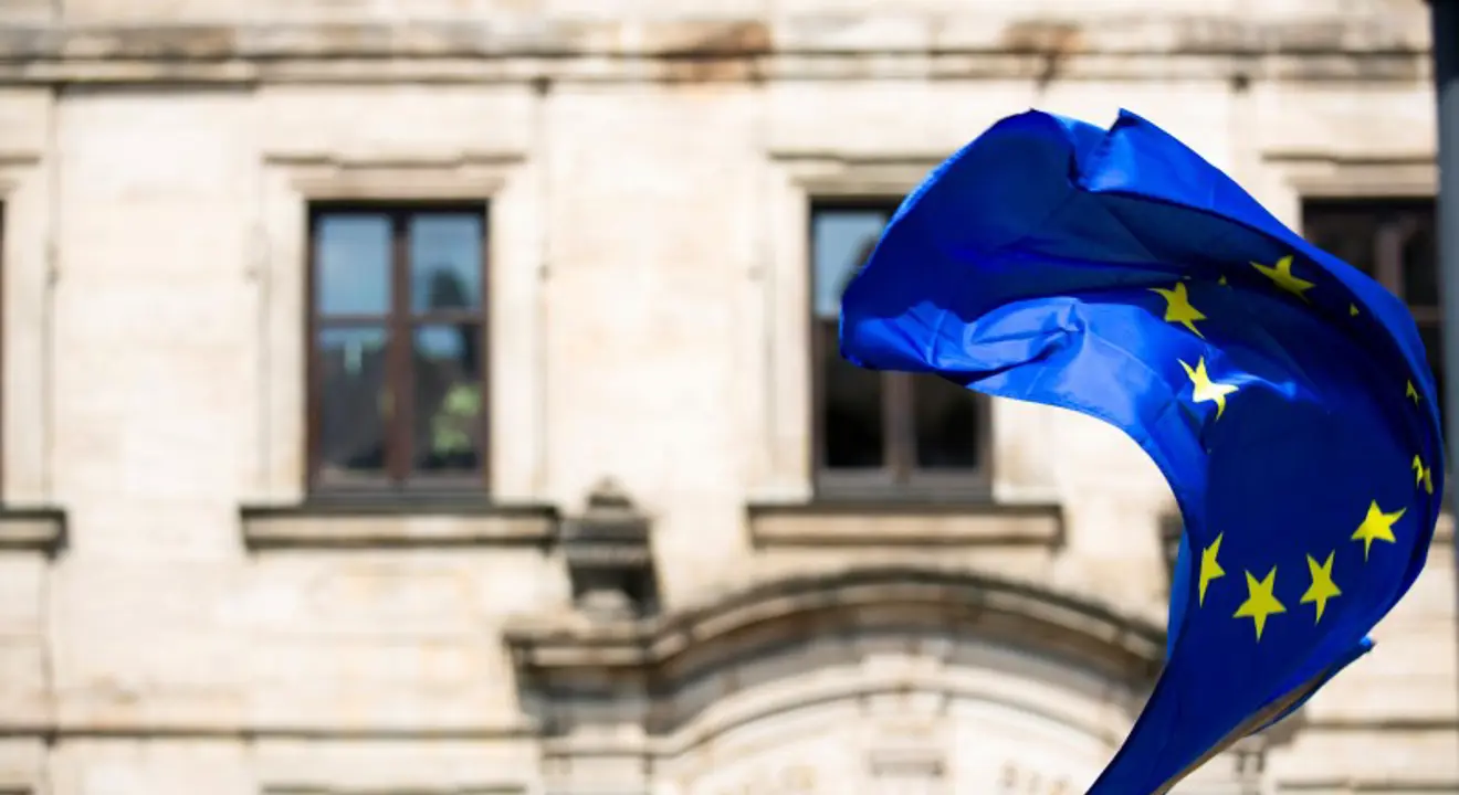EU-flagg vaier i vinden foran en eldre steinbygning. Foto: Markus Spiske/Unsplash