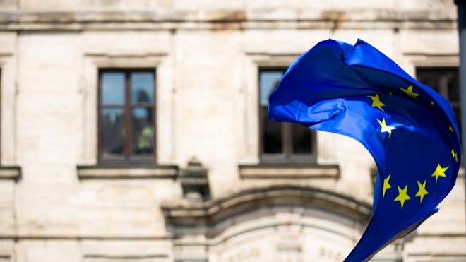 EU-flagg vaier i vinden foran en eldre steinbygning. Foto: Markus Spiske/Unsplash