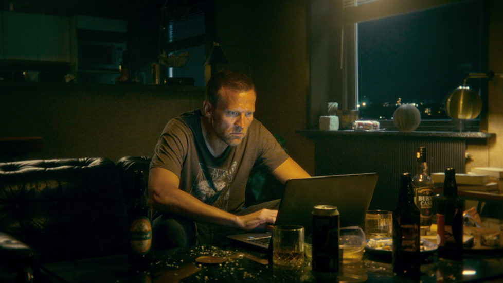 En scene fra den nye Netflix-serien om Harry Hole. Hole sitter ved pc-en i et mørkt rom.