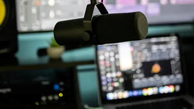 Mikrofon med PC i bakgrunnen, ser ut som radiostudio