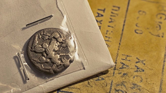Nærbilde av gresk mynt i en konvolutt med plastomslag.