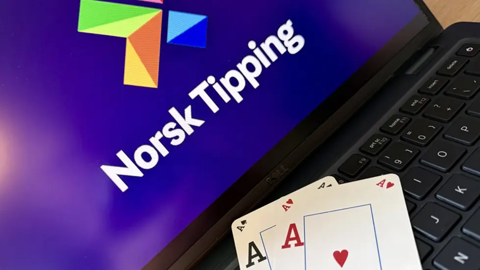 Illustrasjonsbilde: To Ess ligger på tastaturet til n bærbar PC. Norsk Tippings logo er på skjermen.tstokk foran