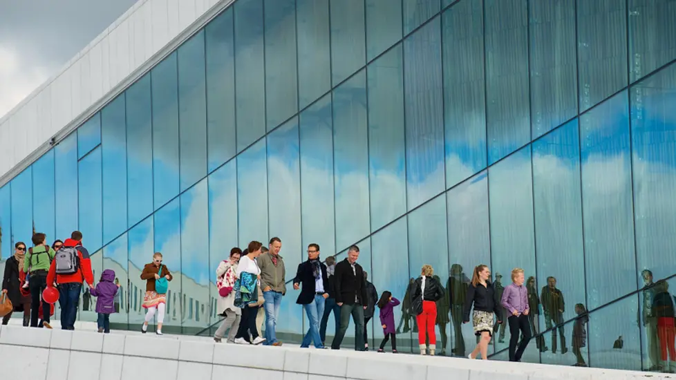 Forsidebildet til OECD-rapporten. Viser fasaden til Den Norske Opera & Ballett, vi ser mange som går nedover taket langs glassveggen.