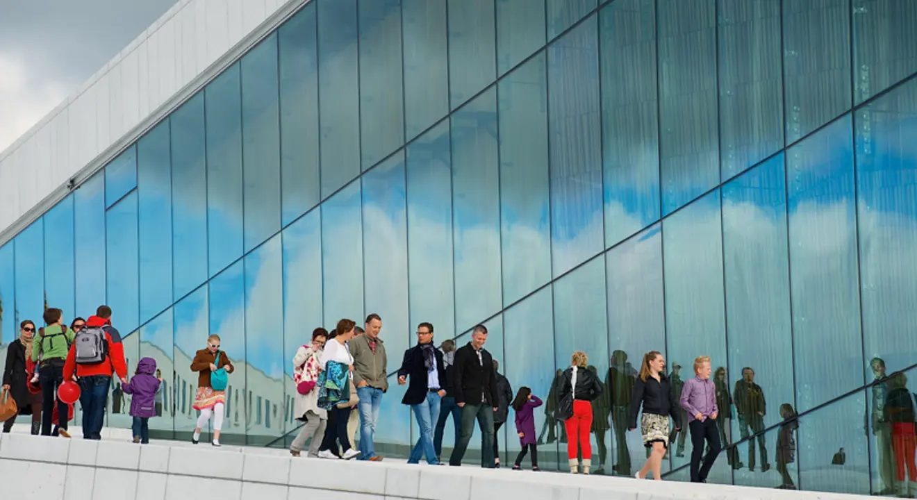 Forsidebildet til OECD-rapporten. Viser fasaden til Den Norske Opera & Ballett, vi ser mange som går nedover taket langs glassveggen.