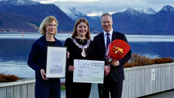 SVV, ordfører og statsråd holder diplom, sjekk og blomster. Poserer foran fjell og vann.