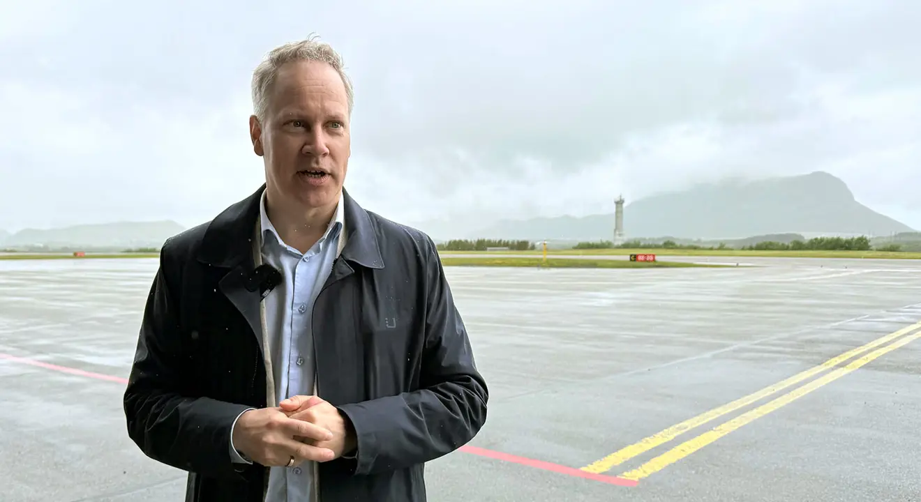 En person står på en rullebane. I bakgrunnen et flytårn.