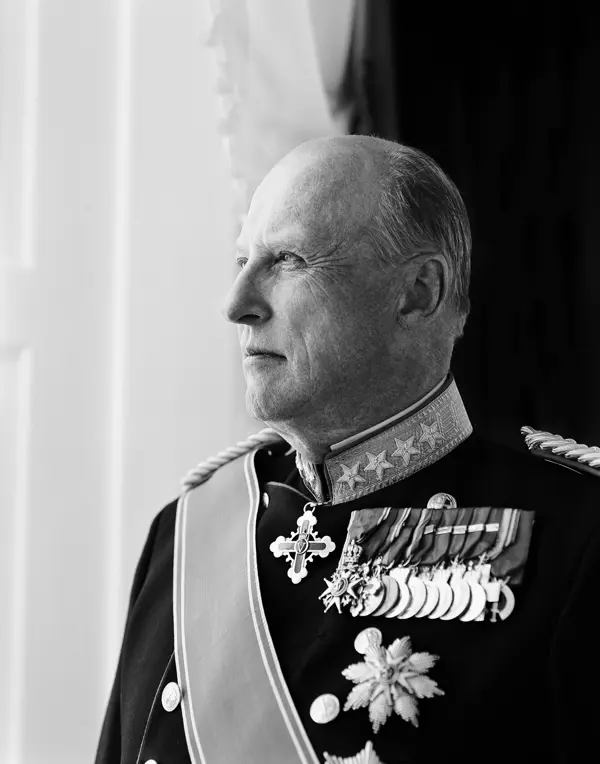 Portrett av Kong Harald i profil, med gallauniform med ordener og medaljer. Sort/hvitt-bilde.