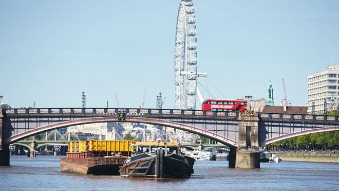 Slepebåten til Cory på Themsen i London. Pariserhjulet London Eye og en bro i bakgrunnen.
