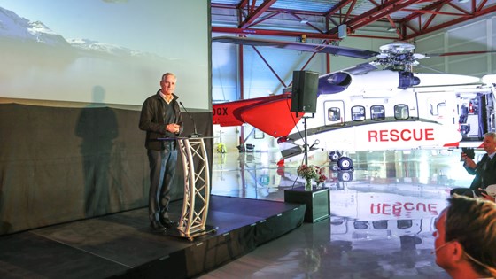 Statsminister Jonas Gahr Støre taler i en hangar ved siden av et redningshelikopter.