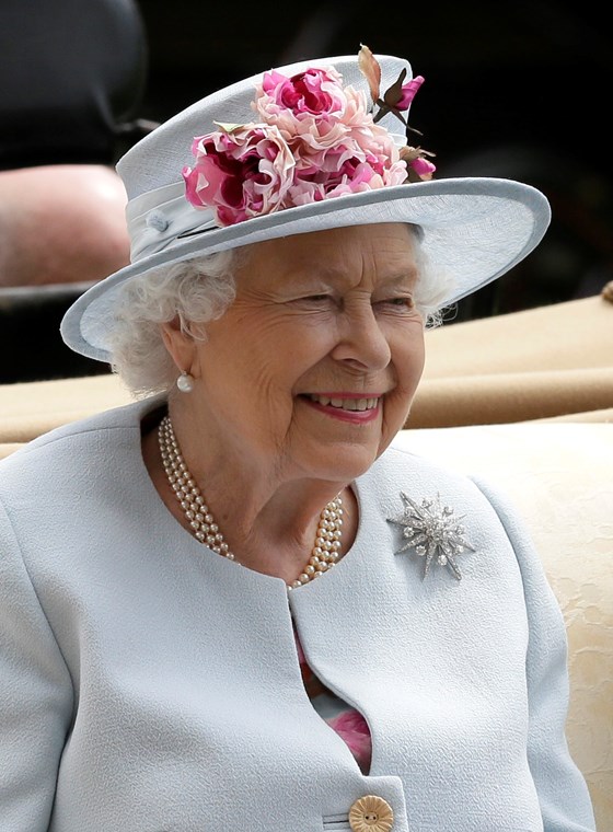 Smiling Queen Elizabeth II in a hat with flowers.