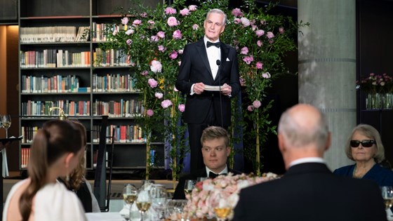Statsminister Jonas Gahr Støre står foran en blomsteroppsats og bokhyller i bakgrunnen.