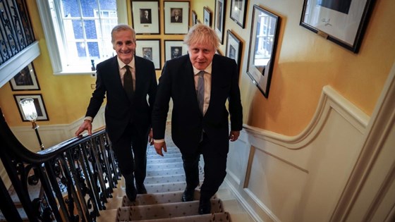 Statsminister Jonas Gahr Støre og statsminister Boris Johnson går opp trappen i Downing Street No 10. Bildegalleri av tidligere statsministre på veggene.