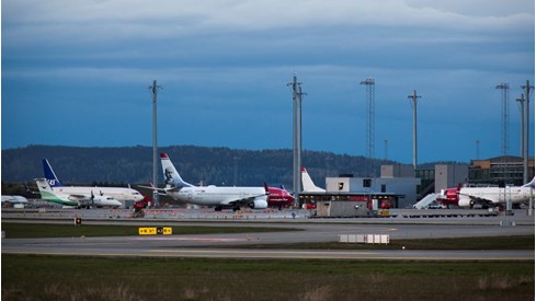 Bilde av en flyplass med fire passasjerfly og terminaler.