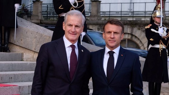 Statsminister Jonas Gahr Støre og Franrikes president Emmanuel Macron står ved siden av hverandre ved inngangen til en bygning i Paris de skal ha bilateralt møte i.