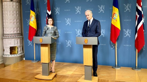 Moldovas president Maia Sandu og statsminister Jonas Gahr Støre står foran blåvegg med riksløver og flaggene til Moldova og Norge i bakgrunnen.