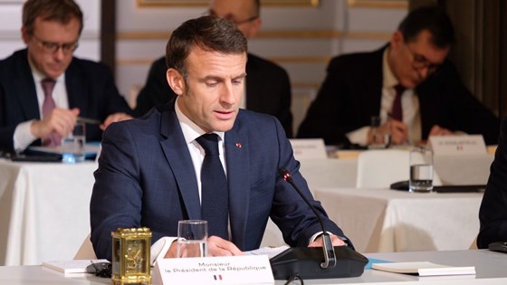 Frankrikes president sitter ved et konferansebord.