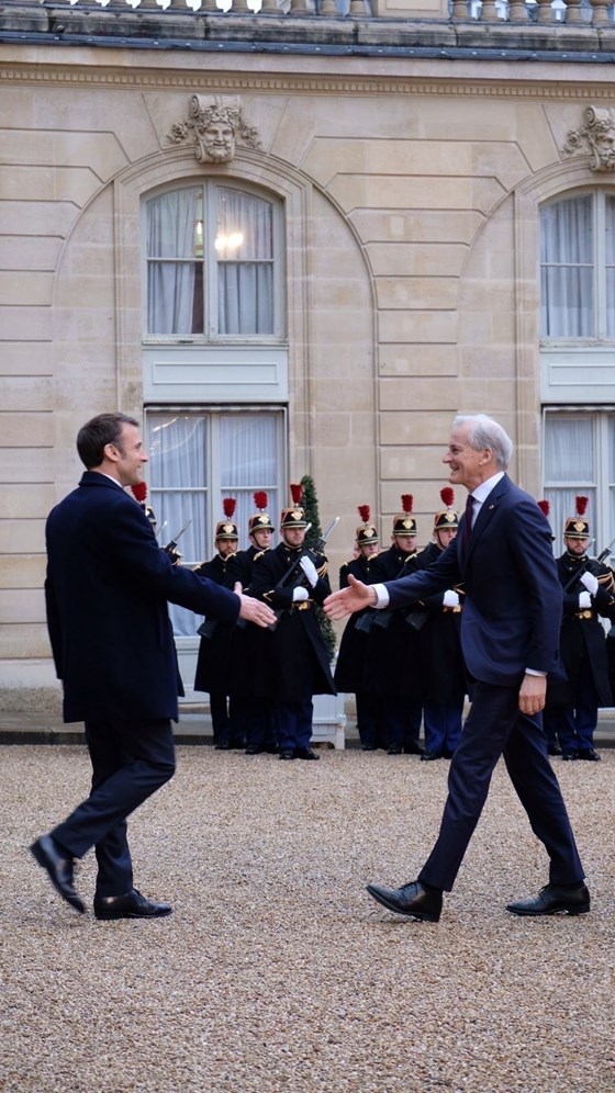 Macron og Støre går mot hverandre med hendene utstrakt - hilser snart på hverandre.