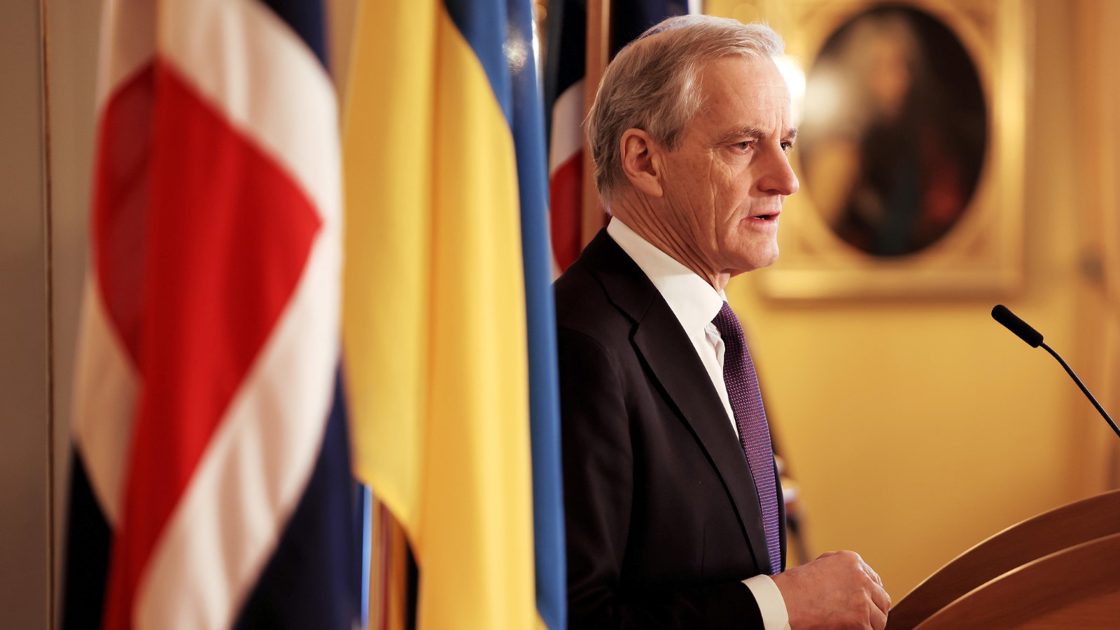 Statsminister Jonas Gahr Støre står ved en talerstol i dress. Med norsk og ukrainsk flagg ved siden av seg.
