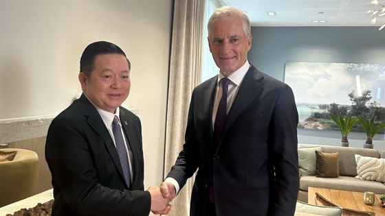 Hourn og Støre står ved siden av hverandre. Håndhilser.