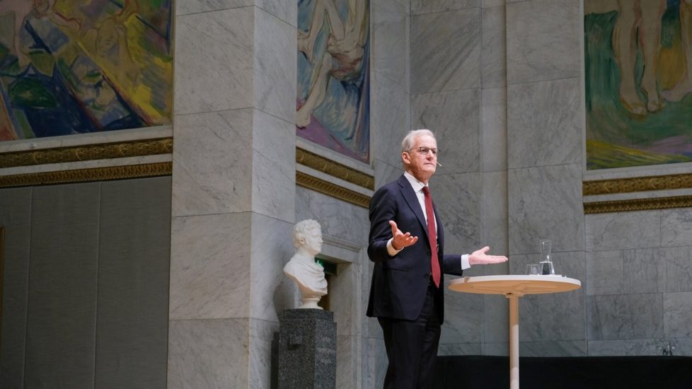 Statsminister Støre gestikulerer med armene underveis i foredraget.