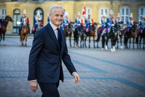 Støre går over brosteinene utenfor slottet. Kledd i dress.