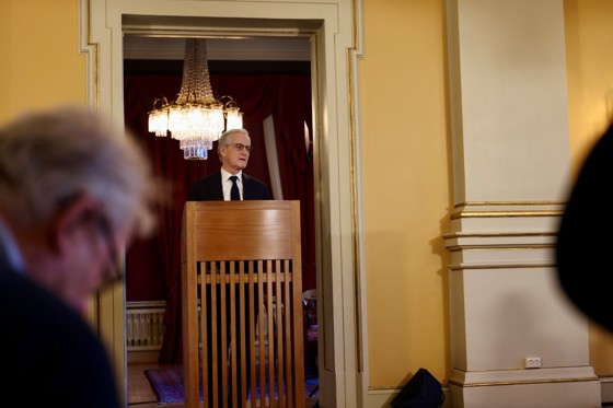 Statsministeren står bak en talerstol. Lyskrone i bakgrunnen.