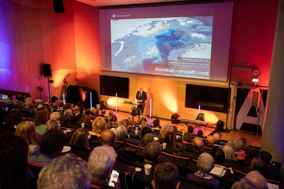 Støre i et auditorium. Studenter hører ham tale.
