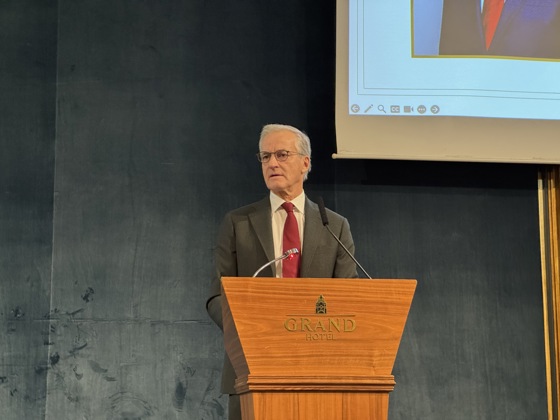 Statsministeren står bak en talerstol på Grand Hotel i Oslo. Dress.