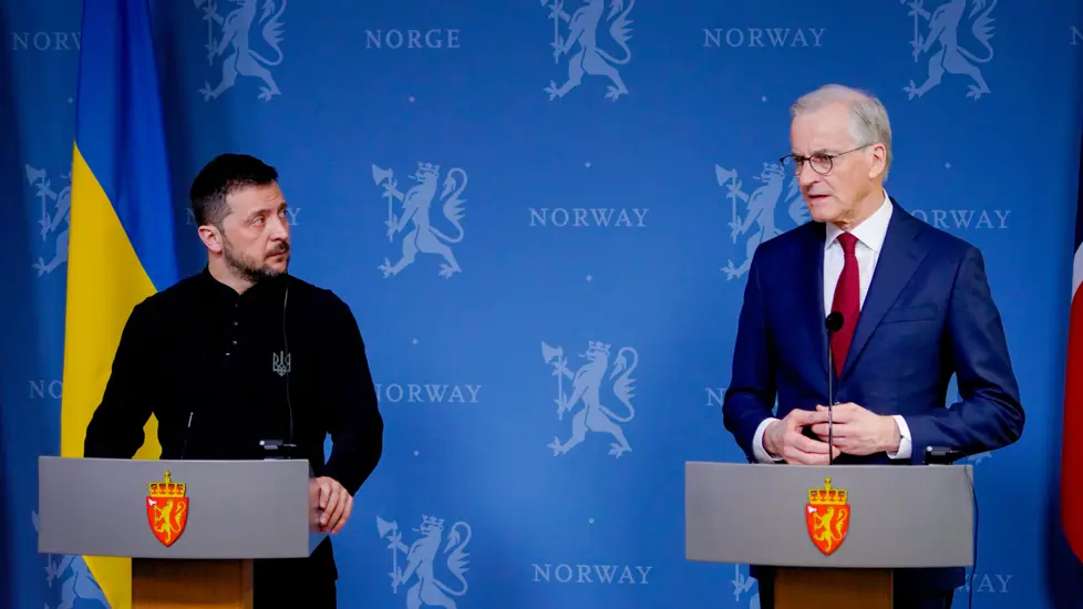 Zelenskyj og Støre står bak hver sin talerstol med riksløve i front. Blå bakgrunn og flagg fra Ukraina og Norge.